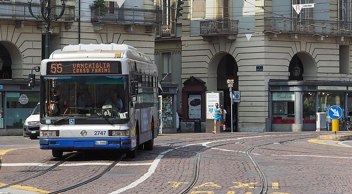 Un autobus pubblico attraversa una piazza con edifici storici a Torino.