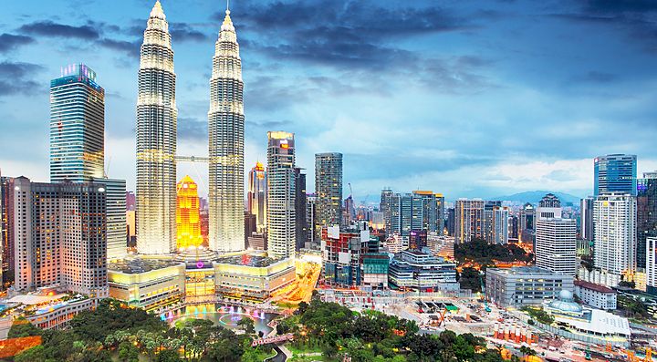 Skyline di Kuala Lumpur con le Torri Petronas illuminate al tramonto.
