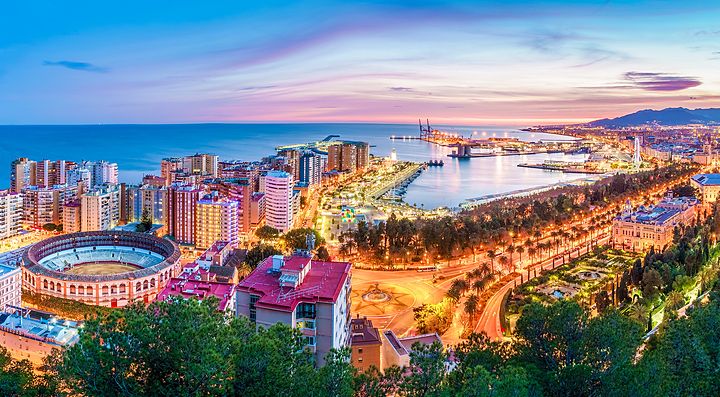 Panorama serale di Malaga con vista sulla città e il porto.