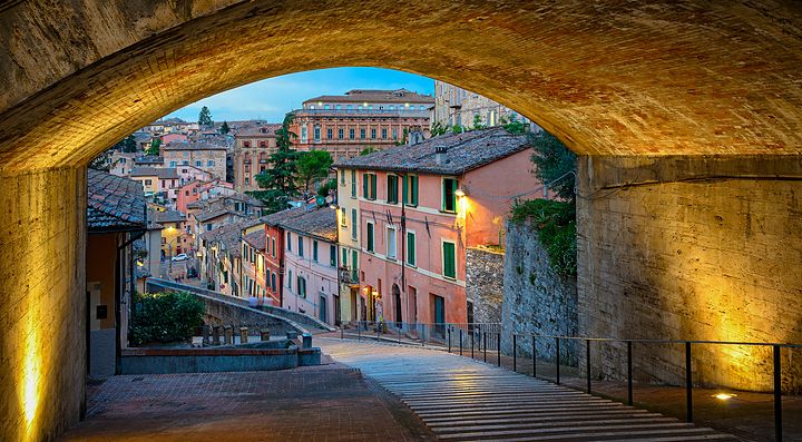 Strada pittoresca con case colorate vista da un arco a Perugia.