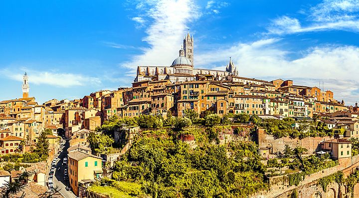 Panorama di Siena con edifici storici e cielo azzurro.