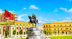 Statua equestre in una piazza di Tirana con bandiera albanese.
