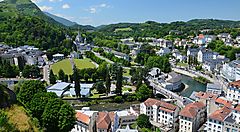 Veduta panoramica di Lourdes con edifici e paesaggio montano.
