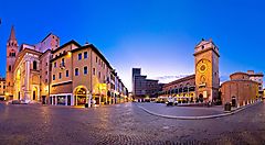 Piazza luminosa a Mantova con edifici storici al tramonto.