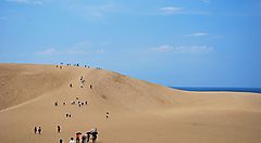 Le dune di sabbia di Tottori sotto un cielo sereno con visitatori.