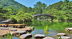 Il giardino Ritsurin con laghetto e ponte di legno immerso nella natura.
