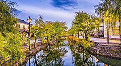 Canale circondato da salici e edifici tradizionali a Kurashiki.