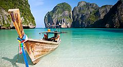 Barca tradizionale sulle acque turchesi di Phi Phi Island, con scogliere in lontananza.