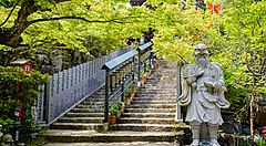 Scalinata del Tempio Daisho-in a Hagi con statue e alberi verdi.