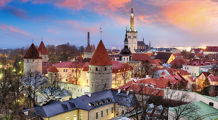 Veduta del centro storico di Tallinn al tramonto con torri medievali.