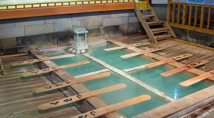 Vasca termale giapponese con pedane in legno, ambiente tradizionale.