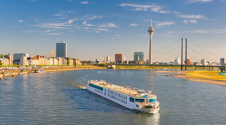 Fiume Reno a Düsseldorf con barca e skyline urbano sullo sfondo.