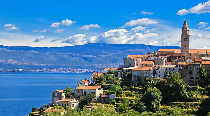 Veduta del paesaggio costiero dell'isola di Krk con edifici storici e mare.