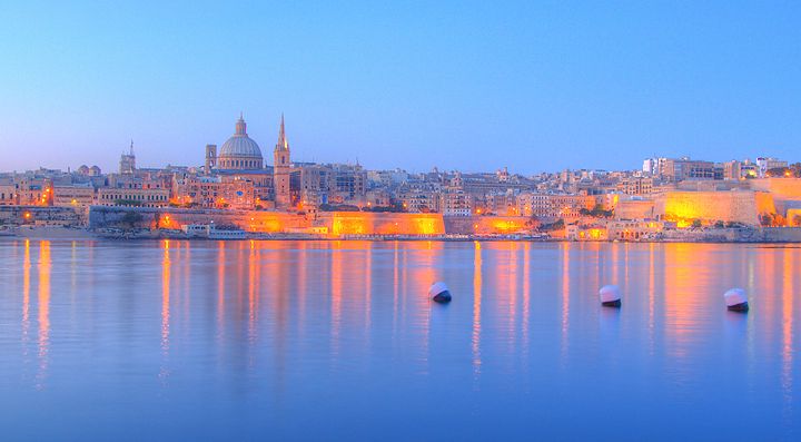 Vista serale di un paesaggio urbano riflesso sul mare a Malta.