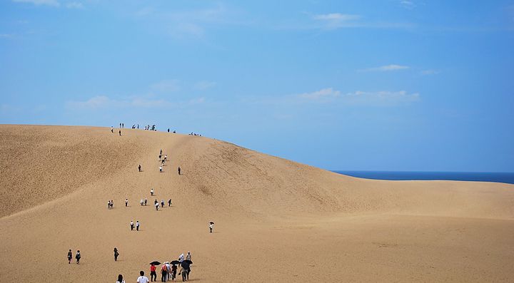 Le dune di sabbia di Tottori sotto un cielo sereno con visitatori.