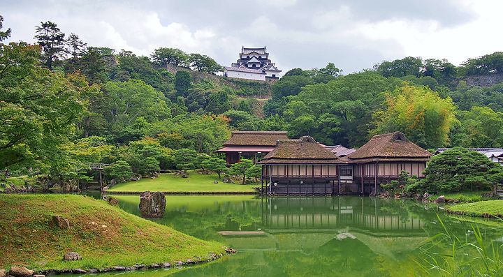 Giardino Genkyuen con laghetto e vegetazione lussureggiante.