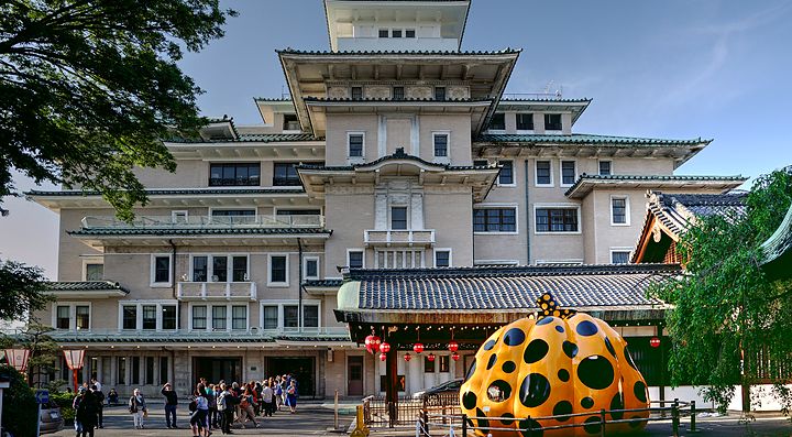 Edificio di stile tradizionale giapponese con scultura moderna davanti.