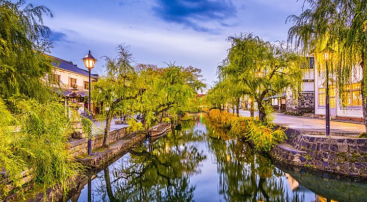 Canale circondato da salici e edifici tradizionali a Kurashiki.