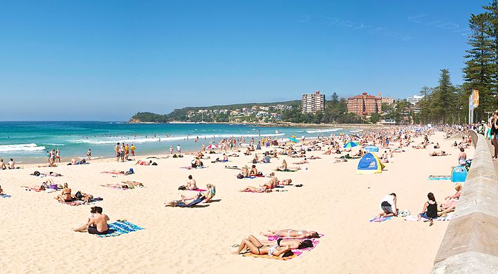 Spiaggia affollata a Manly, Australia, con bagnanti e vista sul mare.