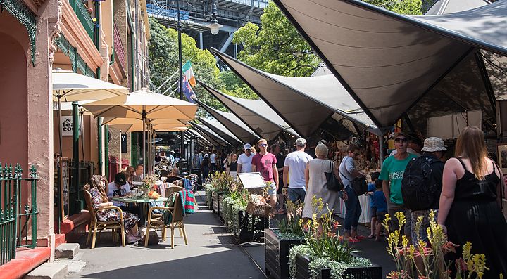 Mercatino all'aperto a Rocks Market, con bancarelle e persone che passeggiano.