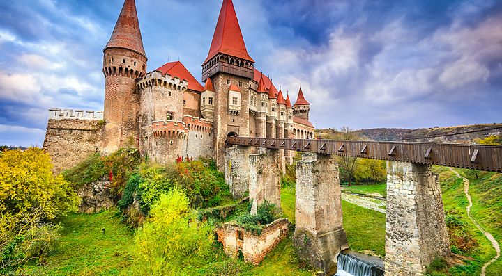 Castello antico in Romania con torri rosse e paesaggio verde.