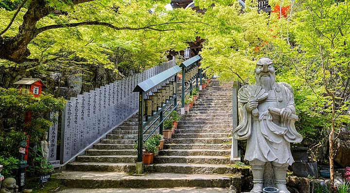 Scalinata del Tempio Daisho-in a Hagi con statue e alberi verdi.