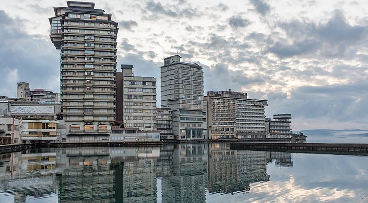 Edifici moderni di Wakura Onsen riflessi nell'acqua al tramonto.