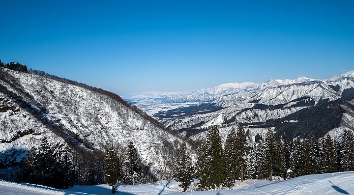 Paesaggio invernale a Yuzawa con montagne innevate e cielo blu.