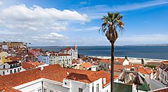 Vista panoramica di un paesaggio urbano in Portogallo con tetti rossi e mare sullo sfondo.