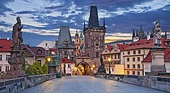 Ponte Carlo a Praga al tramonto con statue e torri storiche.
