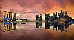 Skyline di Singapore al tramonto riflesso sull'acqua.