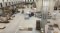 Interno di un magazzino con scatole e pallet disposti sul pavimento.