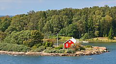 Casetta rossa su un'isola circondata da alberi e acqua in Finlandia.