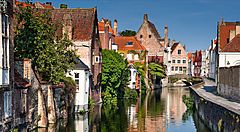 Case storiche lungo un canale in Belgio sotto un cielo blu.