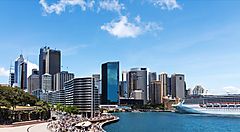 Il Circular Quay di Sydney con grattacieli e una grande nave da crociera.
