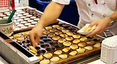 Preparazione di poffertjes olandesi su una piastra calda.