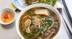 Zuppa di noodle vietnamita con verdure e condimenti a fianco.