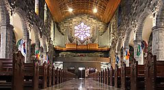 Interno di una chiesa a Galway con vetrate e bandiere.