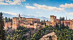 L'Alhambra di Granada circondata da vegetazione e montagne.