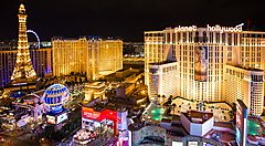 Skyline notturno di Las Vegas con hotel illuminati e Torre Eiffel in lontananza.