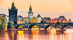 Ponte Carlo a Praga al tramonto con edifici storici sullo sfondo.