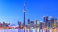 Skyline di Toronto con la CN Tower al tramonto e riflessi sull'acqua.
