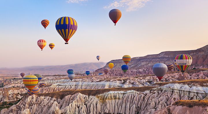Mongolfiere colorate volano sopra i paesaggi rocciosi della Cappadocia, Turchia.