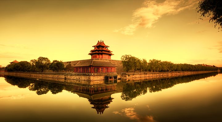 Torre angolare della Città Proibita in Cina riflessa sull'acqua al tramonto.