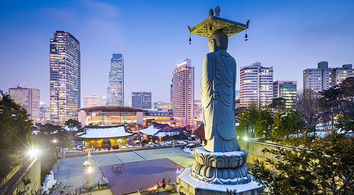 Statua nel tempio Bongeunsa con skyline di Seoul sullo sfondo.