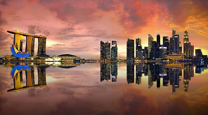 Skyline di Singapore al tramonto riflesso sull'acqua.
