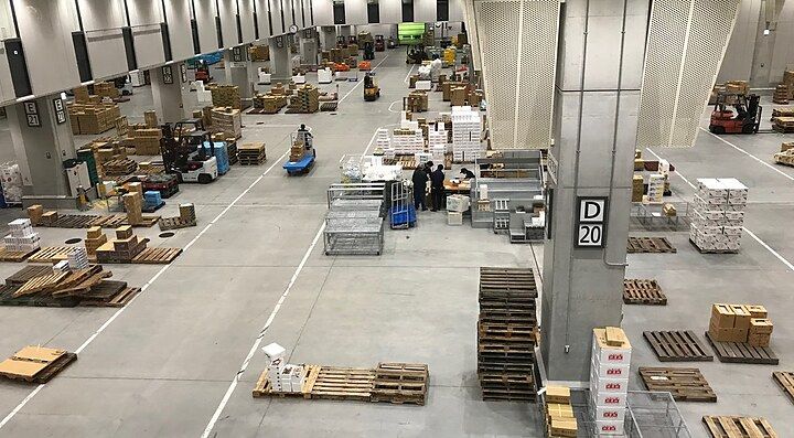 Interno di un magazzino con scatole e pallet disposti sul pavimento.