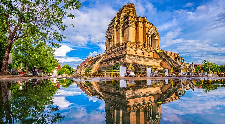 Il Wat Chedi Luang a Chiang Mai riflesso nell'acqua con cielo blu.
