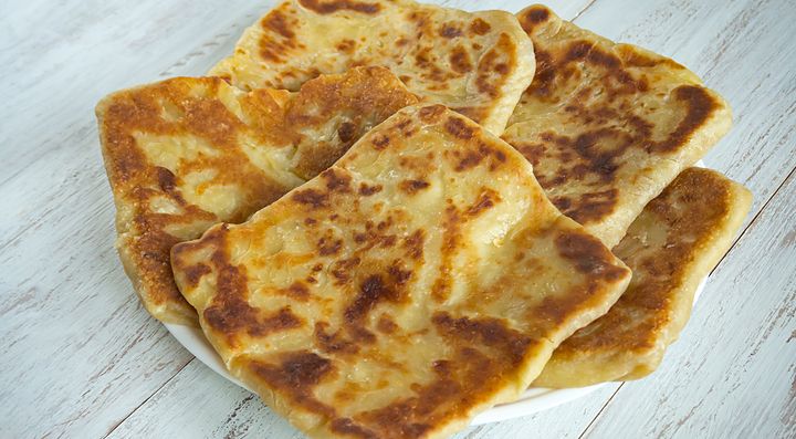 Focaccine rumene su un piatto bianco su tavolo di legno.