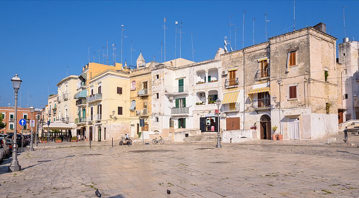 Piazza con edifici storici a Bari sotto un cielo blu terso.